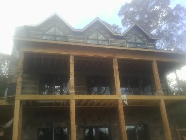 Dormers and porch framing on a large log home under construction — Roof Coating work by our crew in Irvington